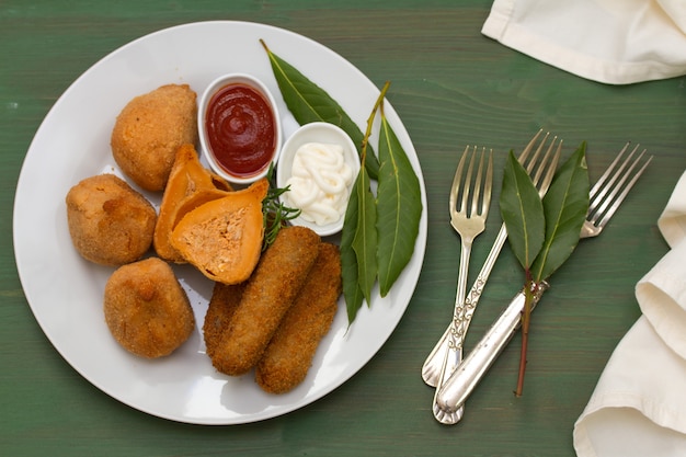 Portuguese appetizers with sauces on white plate on green