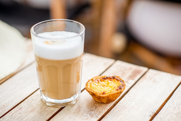 Portuguese coffee galao with sweet dessert pastel de Nata on the table outdoors