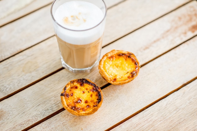 Portuguese coffee galao with sweet dessert pastel de Nata on the table outdoors