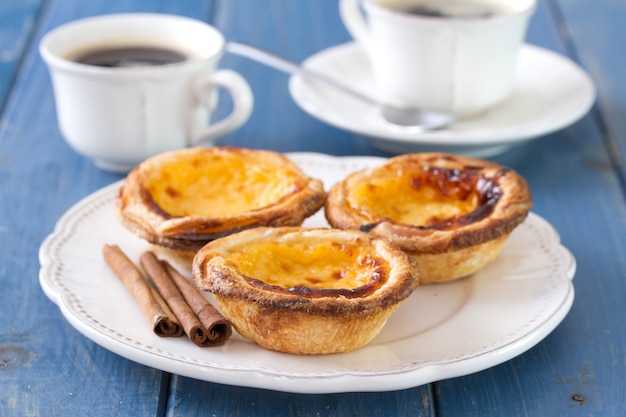 Portuguese cookies on white dish with cups of coffee