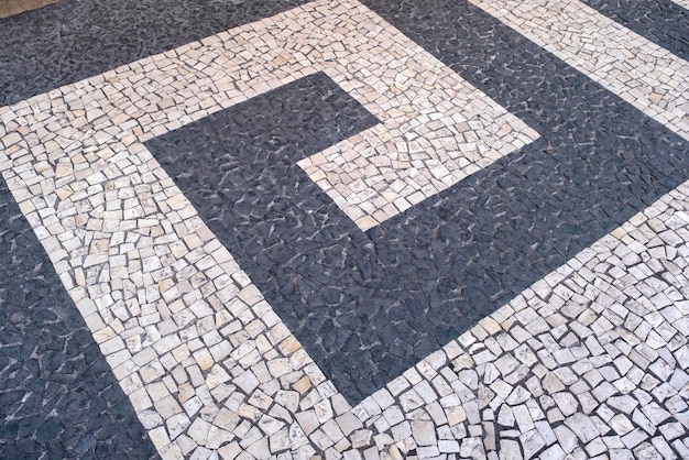 Photo portuguese traditional black and white pavement made from calcada tiling fragment of sidewalk paving