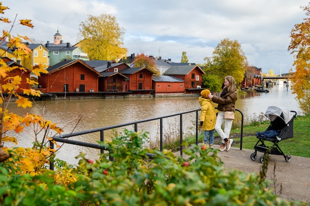  Porvoo, Finland, Mother and son on the river embankment. On the background of old red houses barns