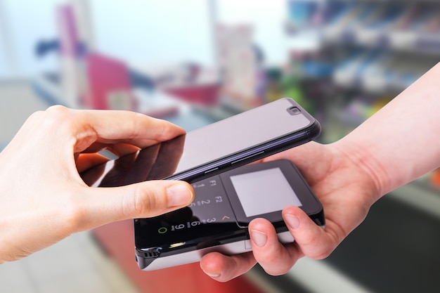 Pos-terminals en smartphone. op de achtergrond is een supermarktkassa. bankapparatuur. verwerven. acceptatie van bankcreditcards. contactloos betalen.