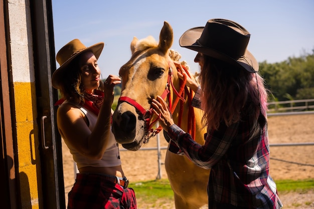 Posed in silhouette of two cowgirl women entering the stable with a horse from a horse, with South American outfits