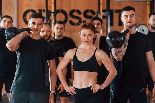 Posing for a camera Group of young sportive people have crossfit day indoors in gym