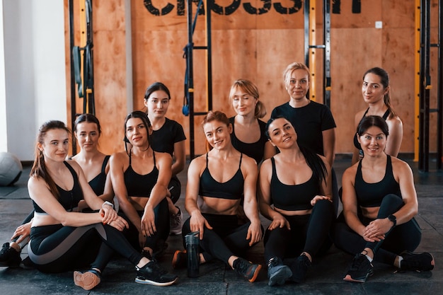 Posing for a camera Group of young sportive people have crossfit day indoors in gym