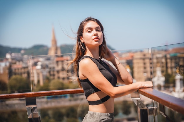 Posa di una giovane donna sulla terrazza di un hotel che guarda la città dall'alto