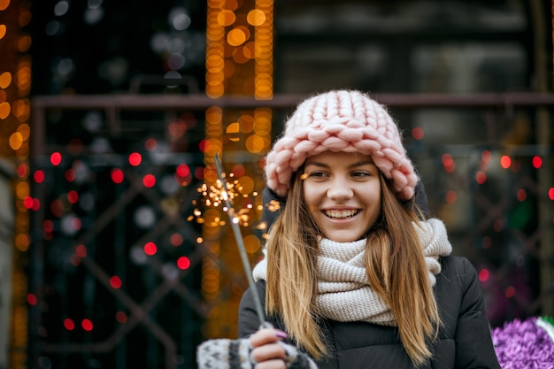 Positief blond meisje met een winteroutfit die Nieuwjaar viert op straat met sterretjes. Ruimte voor tekst