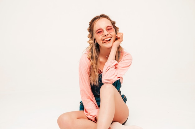 Positief en grappig model poseren op grijze muur in studio in zonnebril