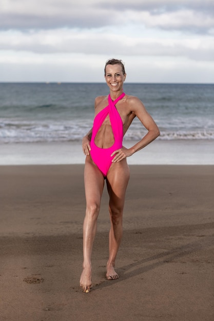 Positief fit vrouwtje dat naar de camera op het strand loopt