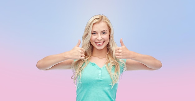 Foto positief gebaar en mensen concept - lachende jonge vrouw of tienermeisje duimen opdagen met beide handen over rozenkwarts en sereniteit verloop achtergrond