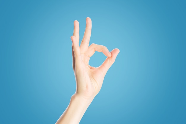 Positief gebaar op een blauw. De hand toont ok teken, omhoog sluit