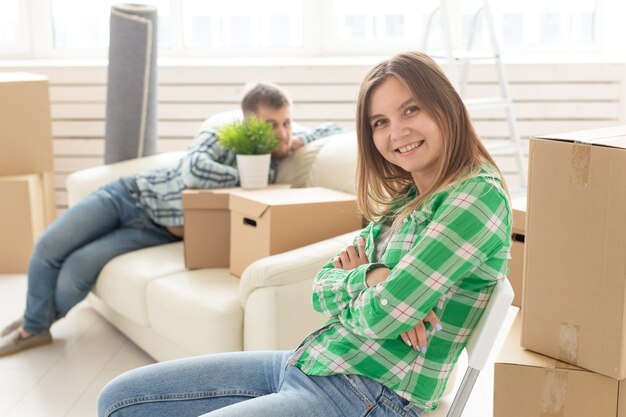 Positief glimlachend jong meisje zittend tegen haar lachende wazig echtgenoot in een nieuwe woonkamer tijdens het verhuizen naar een nieuw huis. Het concept van vreugde door de mogelijkheid om nieuwe huisvesting te vinden.