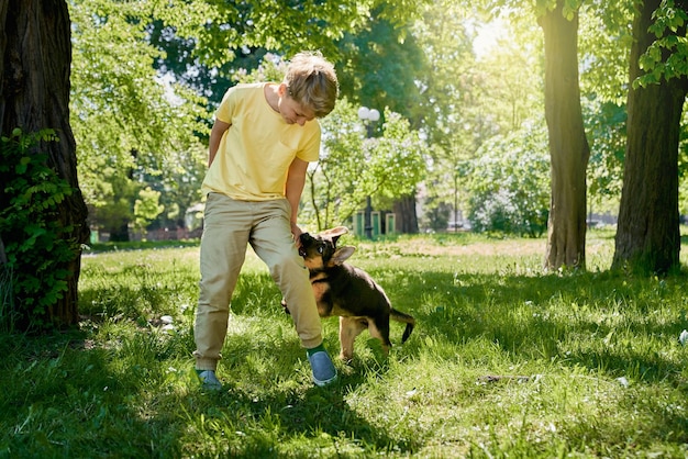 Foto positief kind dat plezier heeft met puppy in zomerpark