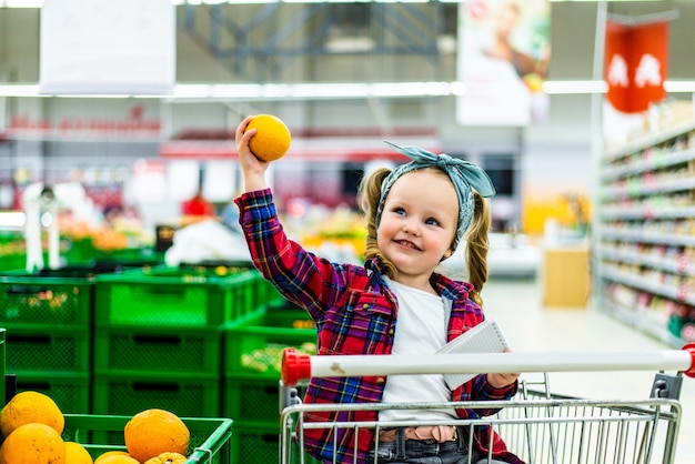 Positief meisje mandarijnen in winkel kopen