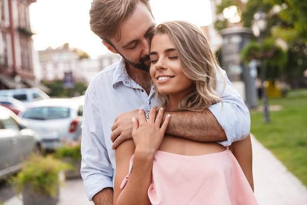 positief optimistisch lachend schattig geweldig jong liefdevol paar wandelen door straat buiten knuffelen.