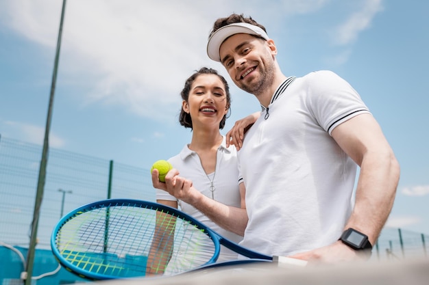 positief paar kijkt naar camera tennis racket en bal zomer activiteit vrije tijd en plezier