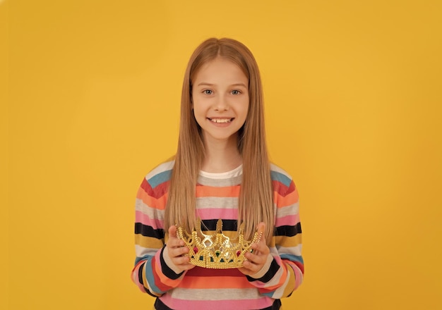 Positief tienerkind houdt koninginkroon vast op gele achtergrond