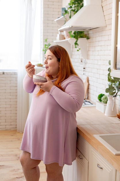 Positieve aardige vrouw die lacht terwijl ze een kom in haar handen houdt