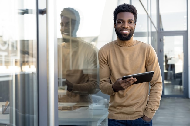 Positieve Afrikaans-Amerikaanse man met een tablet in de hand die buiten staat