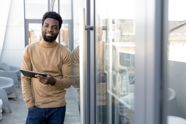 Positieve Afrikaans-Amerikaanse man met een tablet in de hand die buiten staat