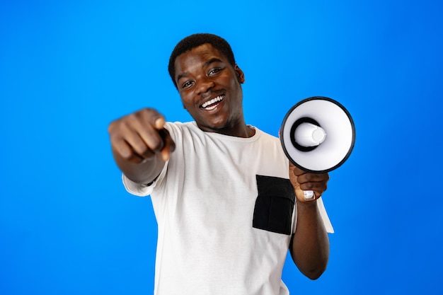 Positieve Afrikaanse man schreeuwt met megafoon op blauwe achtergrond