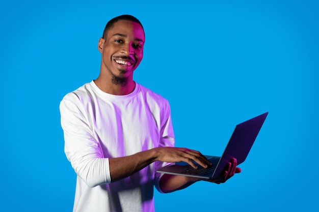 Positieve Afro-Amerikaanse man typen op laptop toetsenbord