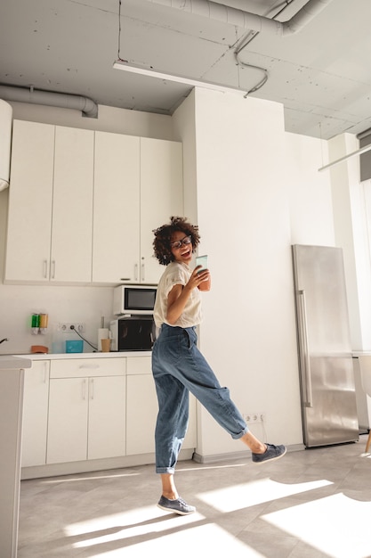 Positieve afro-amerikaanse vrouw met een bril die naar muziek luistert en danst