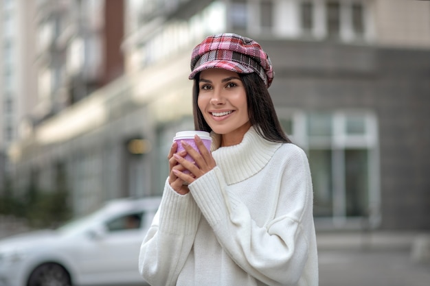 Positieve blije vrouw die lacht terwijl hij een kopje koffie vasthoudt