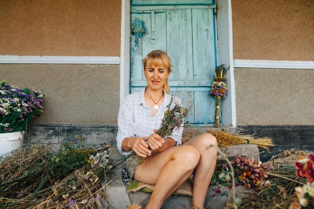 Foto positieve boerin maakt prachtige boeketten van volwassen bloemen op de achtergrond van de muur
