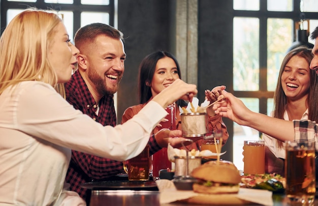 Positieve emoties Groep jonge vrienden die samen in bar zitten met bier