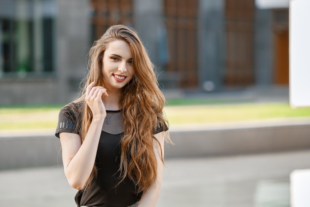 Positieve en gelukkige jonge vrouw met lang krullend haar