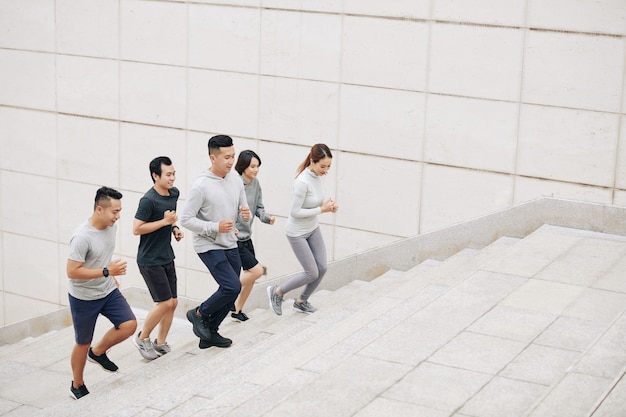 Positieve fitte jonge mannen en vrouwen die de trap op rennen om 's ochtends te trainen voor competitie