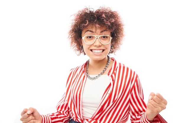 Positieve gelukkige Kazachse meisje met afro kapsel lachen verheugt zich vieren overwinning gehoord goed nieuws geïsoleerd op witte achtergrond