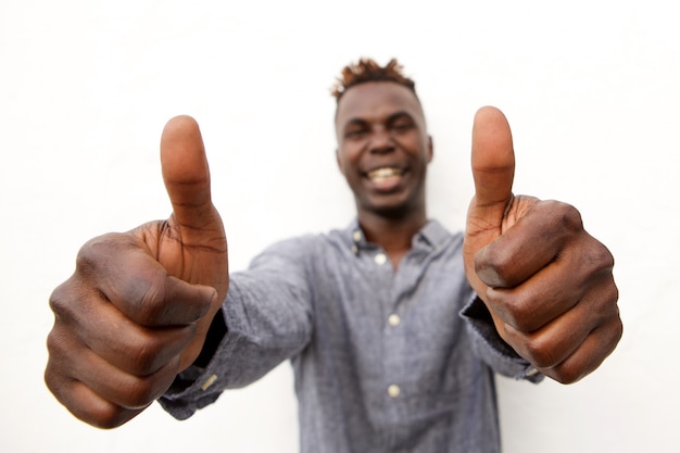 Positieve jonge Afrikaanse mens die met twee omhoog duimen glimlacht