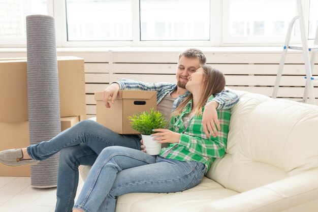 Positieve jonge verliefde man en vrouw zitten op de bank in de nieuwe woonkamer