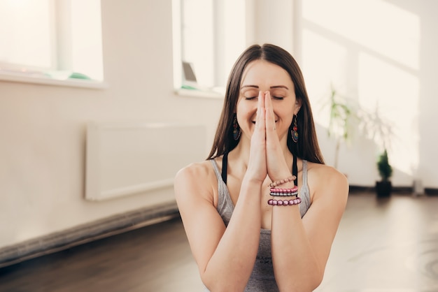 Positieve jonge vrouw die namaste handgebaar doen bij studio