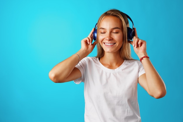 Positieve jonge vrouw luisteren naar muziek met blauwe koptelefoon close-up