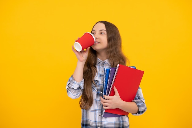 Positieve jongen in geruit hemd met werkboek koffie drinken uit beker op gele achtergrond jeugd