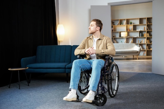 Positieve levensstijlzorg voor revalidatie en ondersteuning van gehandicapten thuis Jonge blanke man in rolstoel in de woonkamer
