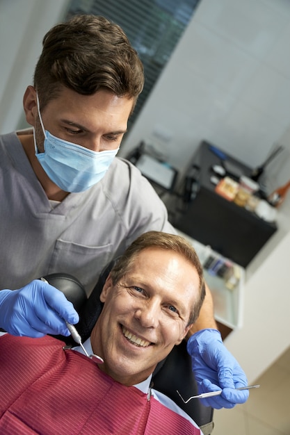 Positieve man die naar de camera kijkt in de tandheelkundige kliniek