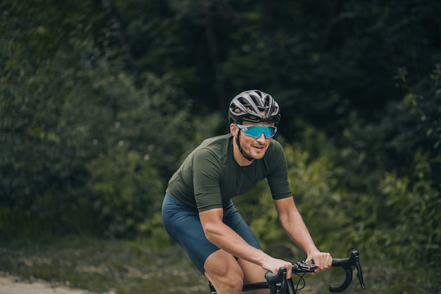 Positieve man in activewear fietsen tussen groen bos