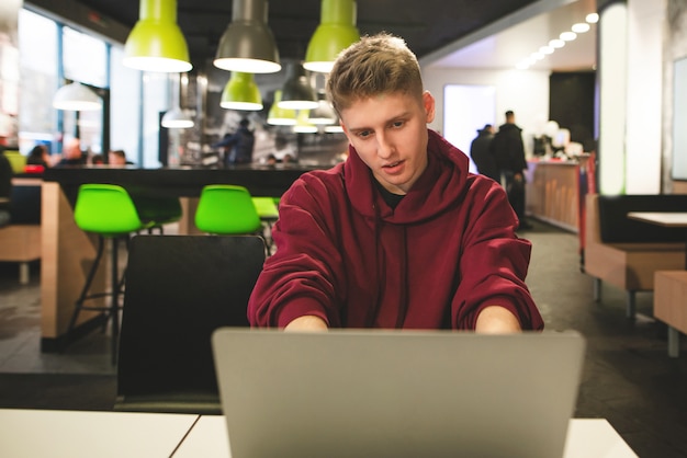 Positieve man werkt op een laptop op de achtergrond van het restaurant