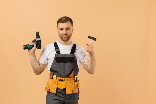 Positieve mannelijke reparateur thuis met hulpmiddelen op beige achtergrond