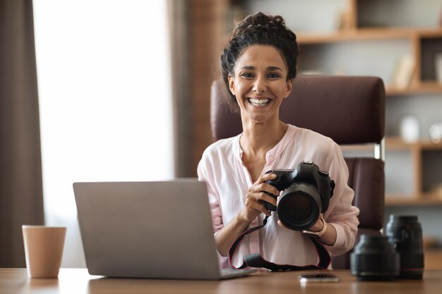 Positieve millennail-damefotograaf die op kantoor aan huis werkt