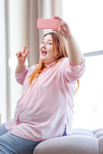 Positieve mollige vrouw die lacht terwijl ze poseert voor een selfie