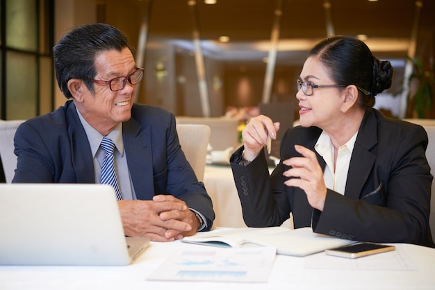 Positieve senior ondernemers ontmoeten elkaar aan de restauranttafel om het marketingplan te bespreken