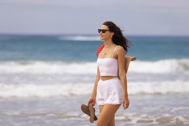 Positieve strandvrouw in stijlvolle zomeroutfit tijdens strandwandelingen