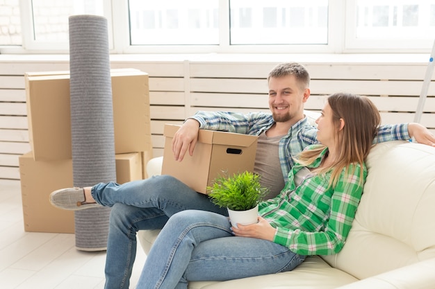 Positieve vrolijke paar verheugt zich in het verhuizen van hun nieuwe appartement zittend in de woonkamer met