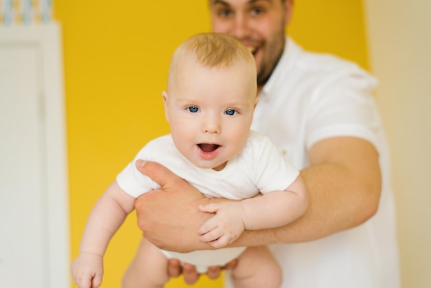 Positieve vrolijke vader houdt zijn zoon in zijn armen close-up foto van de baby